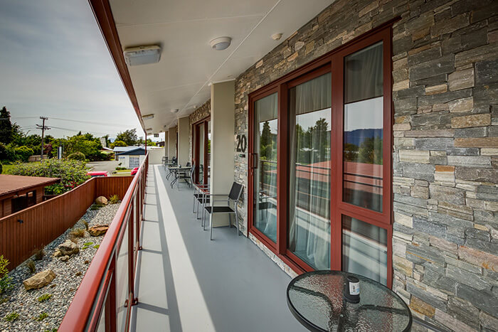 Red Tussock Motel exterior view looking from the balcony towards units with a stone wall